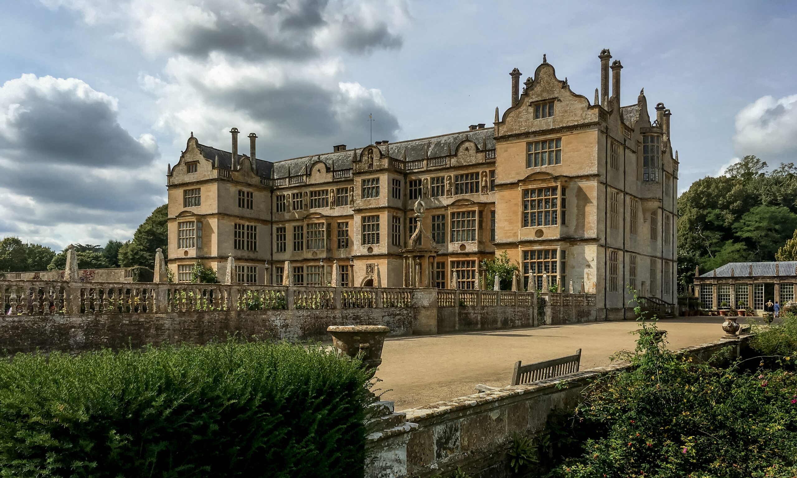 a large stone building with a stone fence and a stone bench