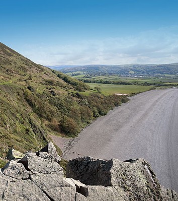 Bossington Beach | A shingle beach stretches to the right with a green hill to the left. There are more hills in the distance