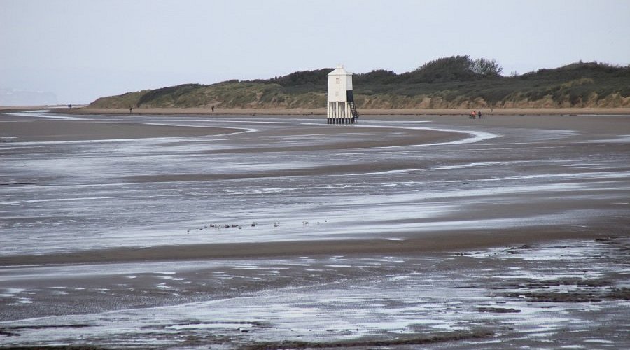 Square wooden lighthouse stands in the middle of mudflats at Burnham On Sea