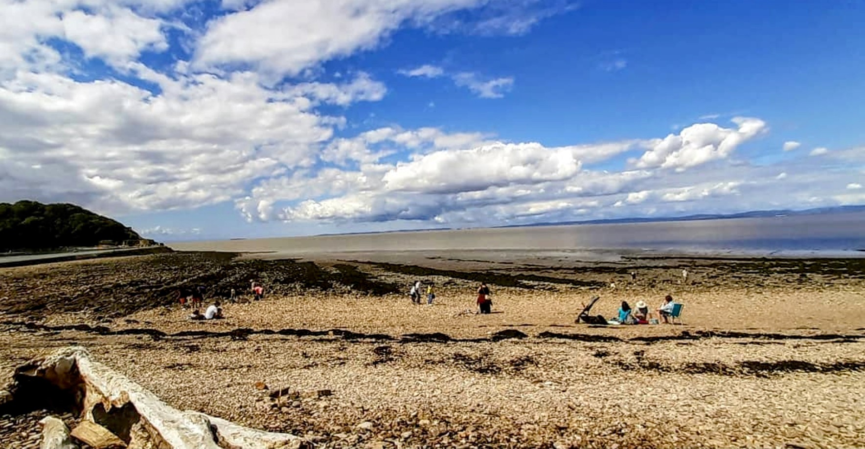 A large expanse of shingle beach at Clevedon with people relaxing and walking